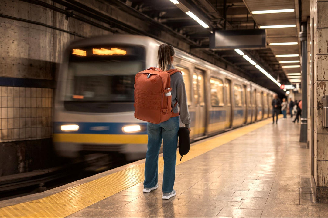 Traveller wearing the CabinZero Military backpack in Maple Leaf on an underground platform as a train arrives.